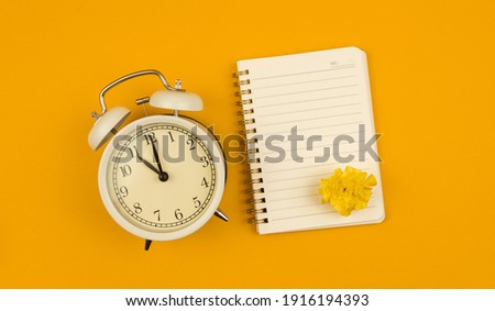 Yellow background with copy space notepad and alarm clock, time managment concept, self-organization composition and banner photo