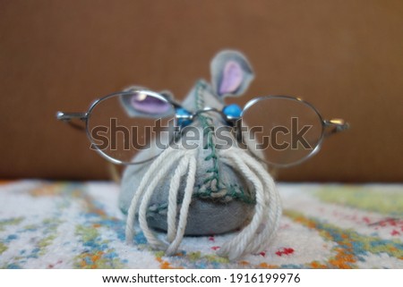 Well-read, intelligent-looking soft toy mouse with old-fashioned glasses that are way too big and faithful blue bulging eyes. Pure Uglyness . Nerdy rat knowledge science concept image portrait .