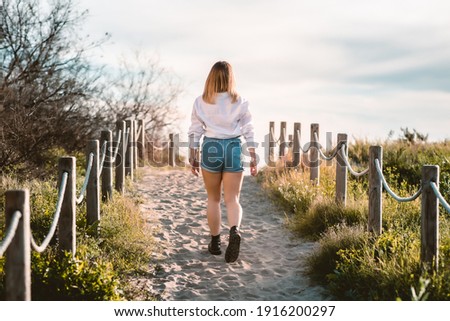 blond girl walking away to the beach