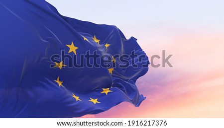 Flag of the European Union waving in the wind on flagpole against the sky with clouds on sunny day Royalty-Free Stock Photo #1916217376