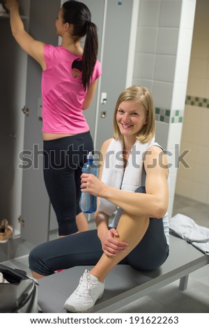 Happy woman with friend in background at gym's locker room