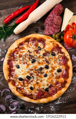 Homemade Meat Loves Pizza with Pepperoni Sausage, Whole traditional italian pepperoni pizza on wooden table with ingredients