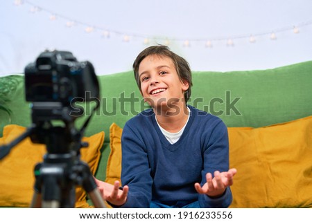 A Blogger boy filming video for his subscribers from home, speaks directly to the camera