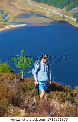 Tourist standing on the rock over the valley with lake and mountains in the background in Wicklow National Park.