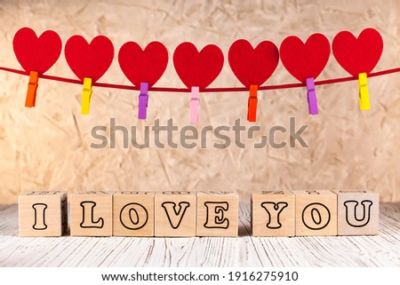 A plea card. Wooden cubes with the inscription I love you. A garland of seven red hearts. Valentines day greeting card.