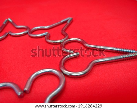 Shape of hearts made from screws isolated on red backgroud. Creative love concept for Valentine's day. Selective focus. 
