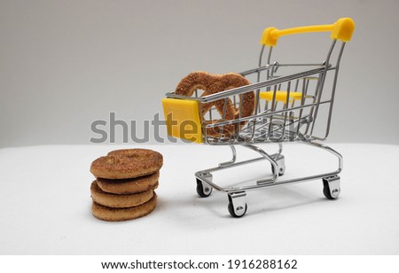 Yellow shopping cart with cookies on a white and gray background. Concept of online shopping. Bakery or grocery store.  Free space for text. Small shopping trolley