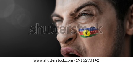 A screaming man with the image of the New Caledonia national flag on his face
