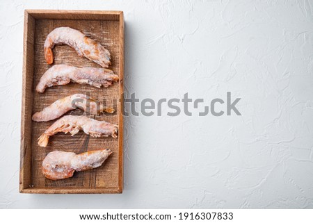 Frozen wild Argentinian red shrimps with heads set, in wooden box, on white background, top view flat lay , with copyspace and space for text