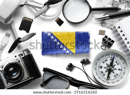 Flag of Bosnia and Herzegovina and travel accessories on a white background. Royalty-Free Stock Photo #1916316260