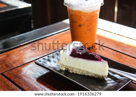 delicious sweet blueberry cheesecake with white cream on black ceramic tray  on wooden table in bakery shop cafe