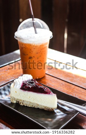 delicious sweet blueberry cheesecake with white cream on black ceramic tray  on wooden table in bakery shop cafe