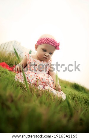 Cute happy blonde blue eyes girl 8 months old in grass. Conceptual photo for education, healthy childhood, parenting, design landscape. Perfect caucasian infant on nature summer. Copy space for site