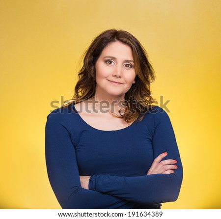 Closeup portrait, happy, confident, successful, pretty young woman in blue shirt with arms crossed folded, isolated yellow background. Positive human emotions, facial expressions, feelings, attitude