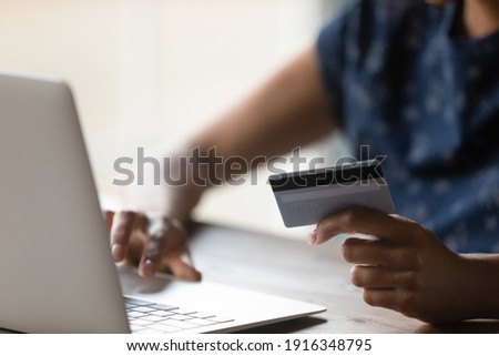 Close up African American woman shopping purchasing online, using laptop, typing, entering information, checking balance, browsing internet banking service, paying by credit card, making payment Royalty-Free Stock Photo #1916348795