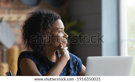 Close up profile satisfied African American woman lost in thoughts, looking to aside, visualizing future, dreaming about new opportunities, pondering strategy, distracted from laptop and online work Royalty-Free Stock Photo #1916350031