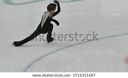 Young figure skater in
  black suit on the ice rink