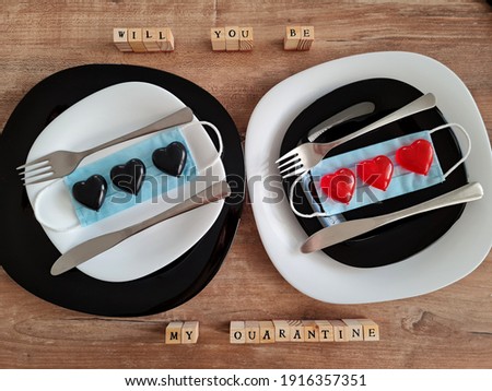 medical face masks with hearts on plates. romantic dinner.  celebrating valentines day in 2021. coronavirus pandemics. lockdown idea. fork and knife. wooden table. will you be my quarantine
