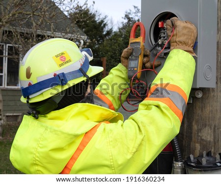 Female electrician measuring volts at a meter base with a voltmeter Royalty-Free Stock Photo #1916360234