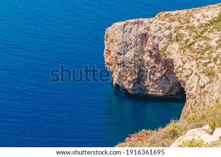 Blue Grotto in Malta. Pleasure boat with tourists runs. Natural arch window in rock.