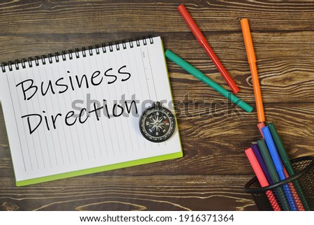 Flat lay of book, compass and colourful pen with wording Business Direction. Business concept.