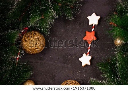 New Year and Christmas background, Christmas tree branches and toys, gift boxes, gingerbread, on a black textured background, free space for design top view
