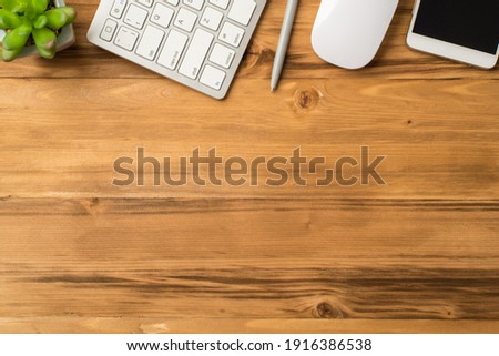 Overhead close up view photo image of cellphone pen white keyboard mouse and green succulent isolated light loft brown backdrop with empty space