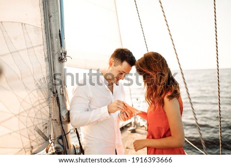 A guy puts a ring on his girlfriend, a marriage proposal on a yacht, she said YES. Royalty-Free Stock Photo #1916393666