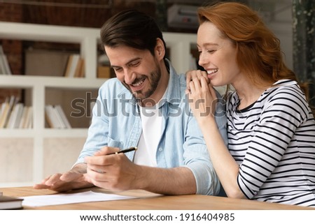 Overjoyed young Caucasian couple clients sign paper document make agreement buy first shared house together. Happy man and woman spouses feel excited close deal rent home or take bank loan. Royalty-Free Stock Photo #1916404985