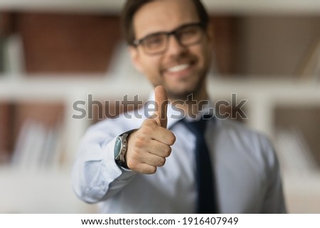Crop close up blurred background of smiling Caucasian man show thumb up give recommendation. Happy male client or customer recommend good quality service or company. Acknowledgment concept. Royalty-Free Stock Photo #1916407949