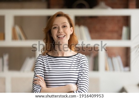 Portrait of smiling young Caucasian businesswoman pose in modern office. Happy 30s red-haired European female employee or worker show leadership and success at workplace. Recruitment concept. Royalty-Free Stock Photo #1916409953