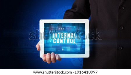 Young business person working on tablet and shows the digital sign: INTERNAL CONTROL