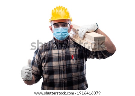 Carpenter worker isolated on white background wears surgical mask to prevent Coronavirus spread, makes OK sign with thumb up. Preventing Pandemic Covid-19 at the workplace.