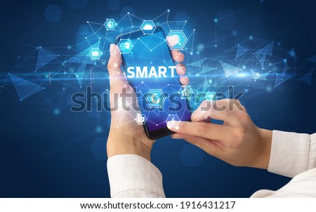 Female hand holding smartphone with SMART inscription, modern technology concept