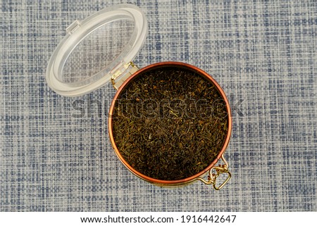 Flat Lay open tea coffee tin with latch. Latch lock tin with dried tea leaves. Sele
