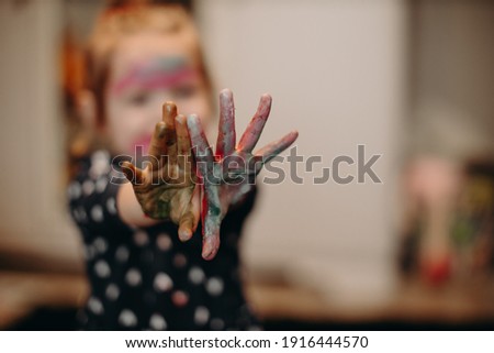 Little girl playing with colors, paints by hand.