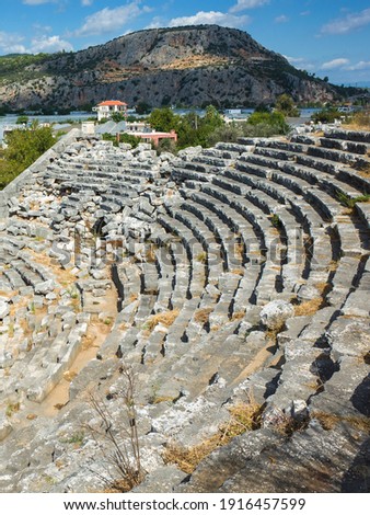 Rows of stone seats of ruins of Theatre in Letoon Ancient City in village Kumluova, Turkey. Sunny day, Greek culture ancient amphitheater architecture vertical photo