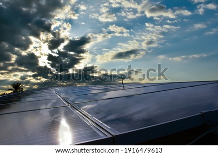 Photovoltaic panels on the roof's building with sunrise and cloudy blue sky background, concept for using natural energy to reduce global warming and expenses from the use of electricity in the house.