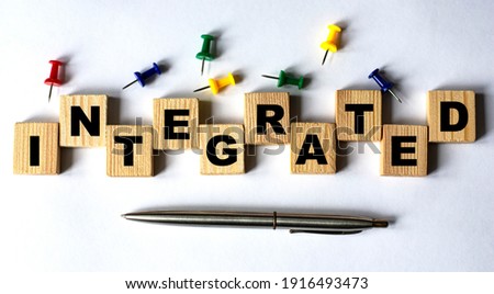 INTEGRATED - word on wooden cubes with stationery buttons, pen on white background. Business concept