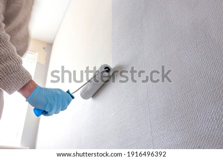 Man painting wall using a paint roller. Do it yourself concept Royalty-Free Stock Photo #1916496392