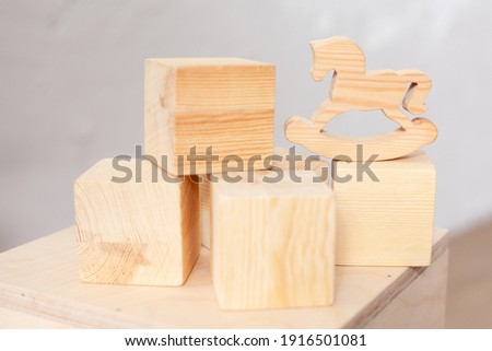 Wooden cubes and a horse for children's games. Child development. Security. Classes with a child. No plastic. Ecology and naturalness. Childhood. Close-up in natural tones. High quality photo