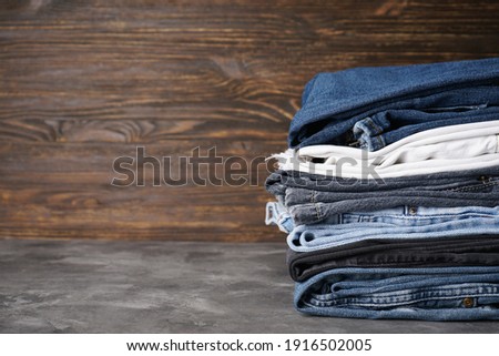 Jeans stacked in a stack, on a wooden background, space for text.