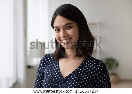 Headshot portrait of happy millennial female student of asian ethnicity. Confident smiling lady receptionist meet guest. Profile picture of young vietnamese woman blogger tutor looking at web camera