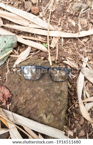 Doff black square glasses on rock and ground
