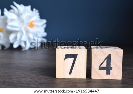 Number 74, rating, award, Empty cover design in natural concept with a number cube and peony flower on wooden table for a background.