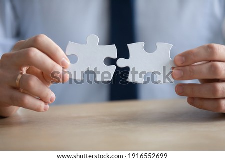 Crop close up of male employee or worker hold assemble jigsaw find best business solution or option. Businessman connect pieces of puzzle think of problem solving. Brainstorm, decision concept.