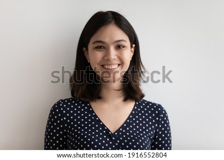 Studio headshot portrait of positive young female of asian ethnicity for social network profile. Pretty smiling millennial vietnamese lady feel happy looking at camera in good mood. Isolated on white
