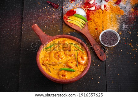 Prawn mango curry,kerala traditional dish made using raw mango and  arranged in an earthen ware with black textured background