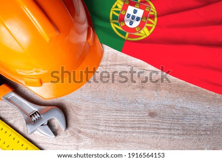 Portugal flag with different construction tools on wood background, with copy space for text. Happy Labor day concept.