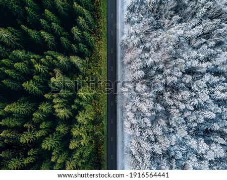 Aerial view of a highway road through the forest in summer and winter. Royalty-Free Stock Photo #1916564441